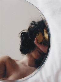 Close-up of woman with reflection in glass