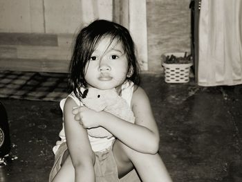 Portrait of cute girl with toy sitting at home