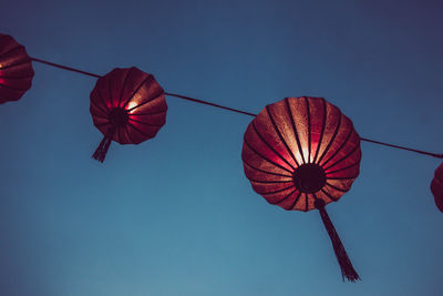 Low angle view of lanterns hanging against clear blue sky