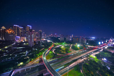 High angle view of illuminated street amidst buildings at night