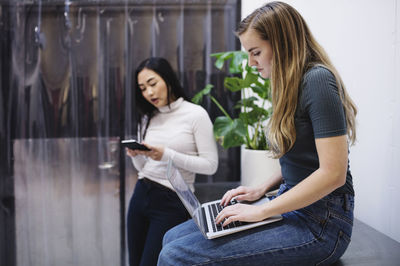 Female bloggers using laptop and smart phone in creative office