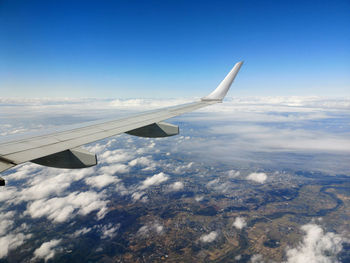 Aerial view of aircraft wing over landscape against sky