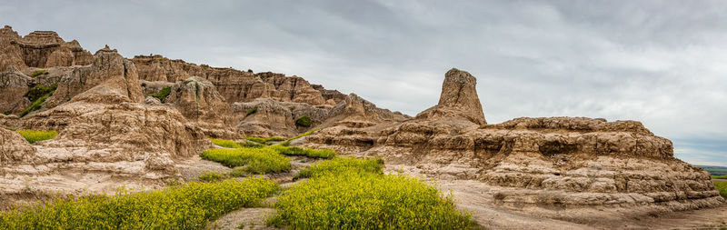 Rock formations on landscape against cloudy sky