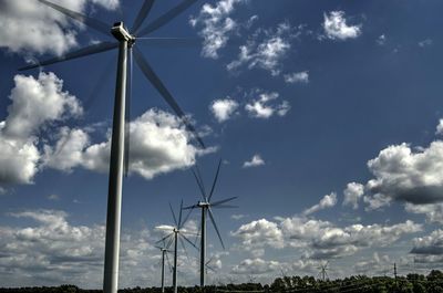 Low angle view of wind turbines in field