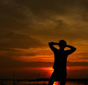 Silhouette man standing against orange sky