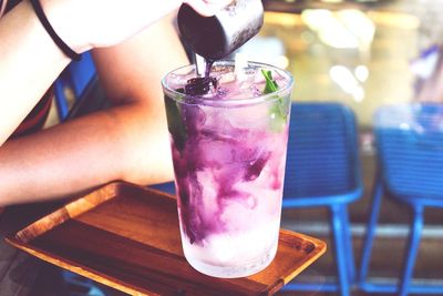 Close-up of hand holding drink on table