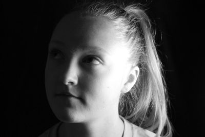 Close-up of teenage girl against black background