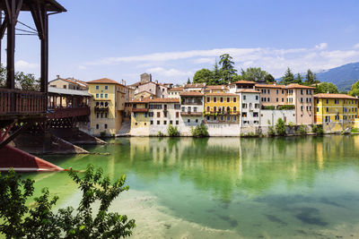 Buildings by river against sky