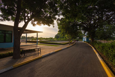 Empty road by trees in city against sky