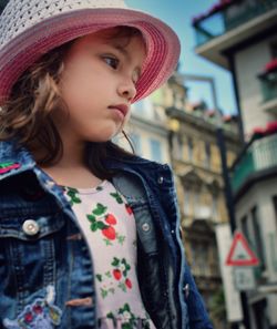 Close-up of girl looking away while standing against buildings in city 