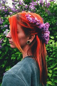 Side view of redhead young woman wearing flowers in hair at park