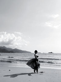 Side view of man on beach against sky