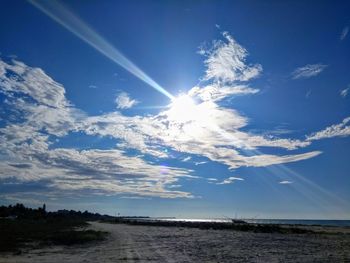 Scenic view of bright sun over field against sky