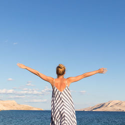 Rear view of man standing by sea against clear sky