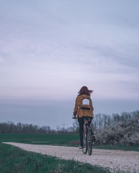 Rear view of man riding bicycle on road