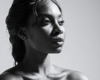 Close-up portrait of young woman against gray background
