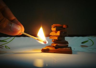 Close-up of hand holding illuminated candles