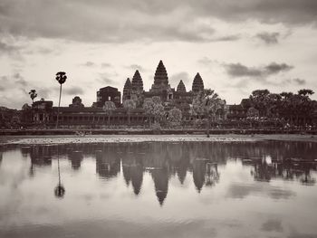 Reflection of temple in lake against cloudy sky