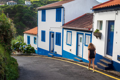 Back view of a teen girl walking down a steep street in los moinhos, porto formoso, azores