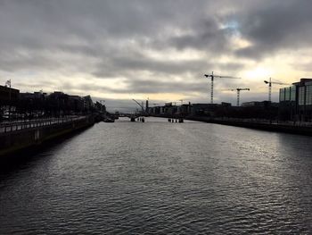 View of city at waterfront against cloudy sky