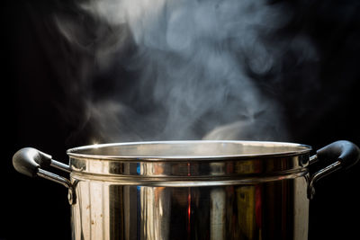 Close-up of cooking pan on barbecue grill against black background
