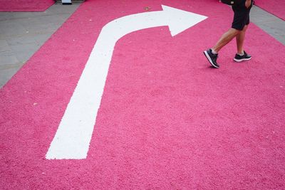 Low section of man running on pink road