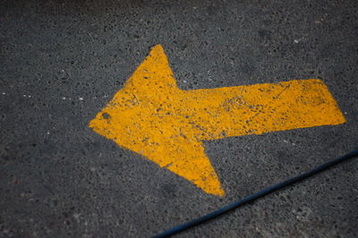 Close-up of yellow arrow symbol on road