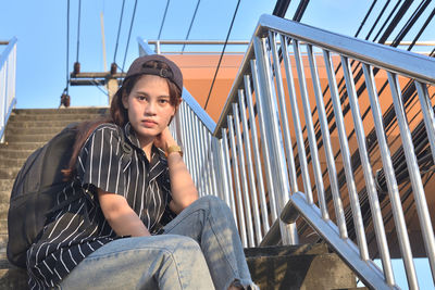 Portrait of young woman sitting on railing