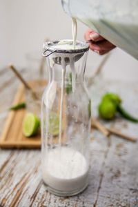 Cropped image of hand pouring drink into glass jar