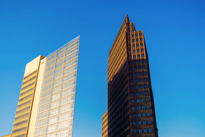 Low angle view of modern buildings against clear blue sky