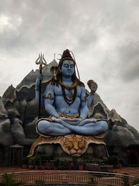 Low angle view of statue against building against sky