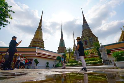 People at temple outside building against sky