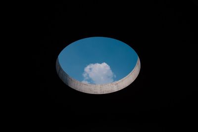 Low angle view of blue sky seen through circular hole