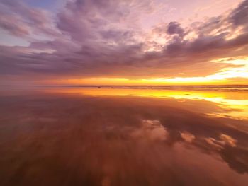 Scenic view of sea against dramatic sky during sunset