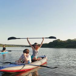 People on boat in lake against sky