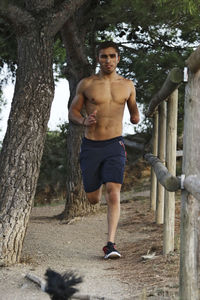 Portrait of physically challenged shirtless man jogging by fence