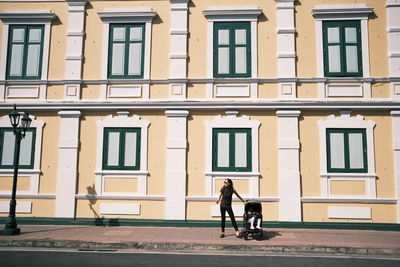 Man riding bicycle on street against building in city