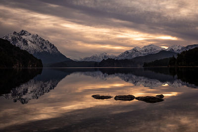 Scenic view of lake by mountains against sky during sunset