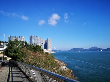 Scenic view of sea by buildings against blue sky