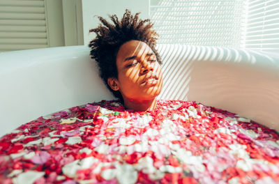 Young woman with flowers in bathtub