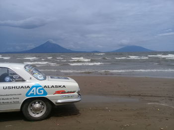 Vintage car on beach against sky