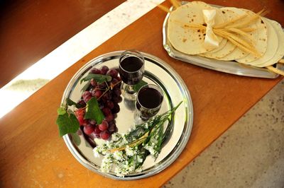 High angle view of red wine with grapes and flowers by flatbread on table