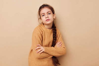 Portrait of young woman standing against pink background