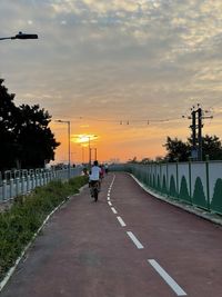 Road by street against sky during sunset