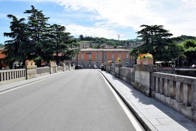 Road by buildings in city against sky