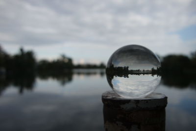 Close-up of water drop on lake against sky