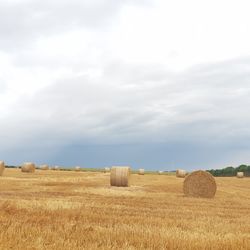 Hay bales on field against sky