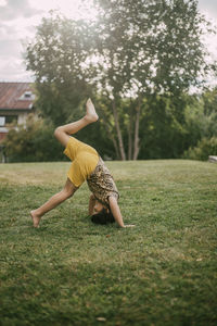 Side view of girl practicing headstand in yard