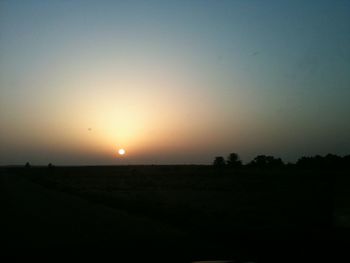 Scenic view of silhouette field against clear sky during sunset