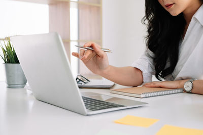 Midsection of woman using laptop on table